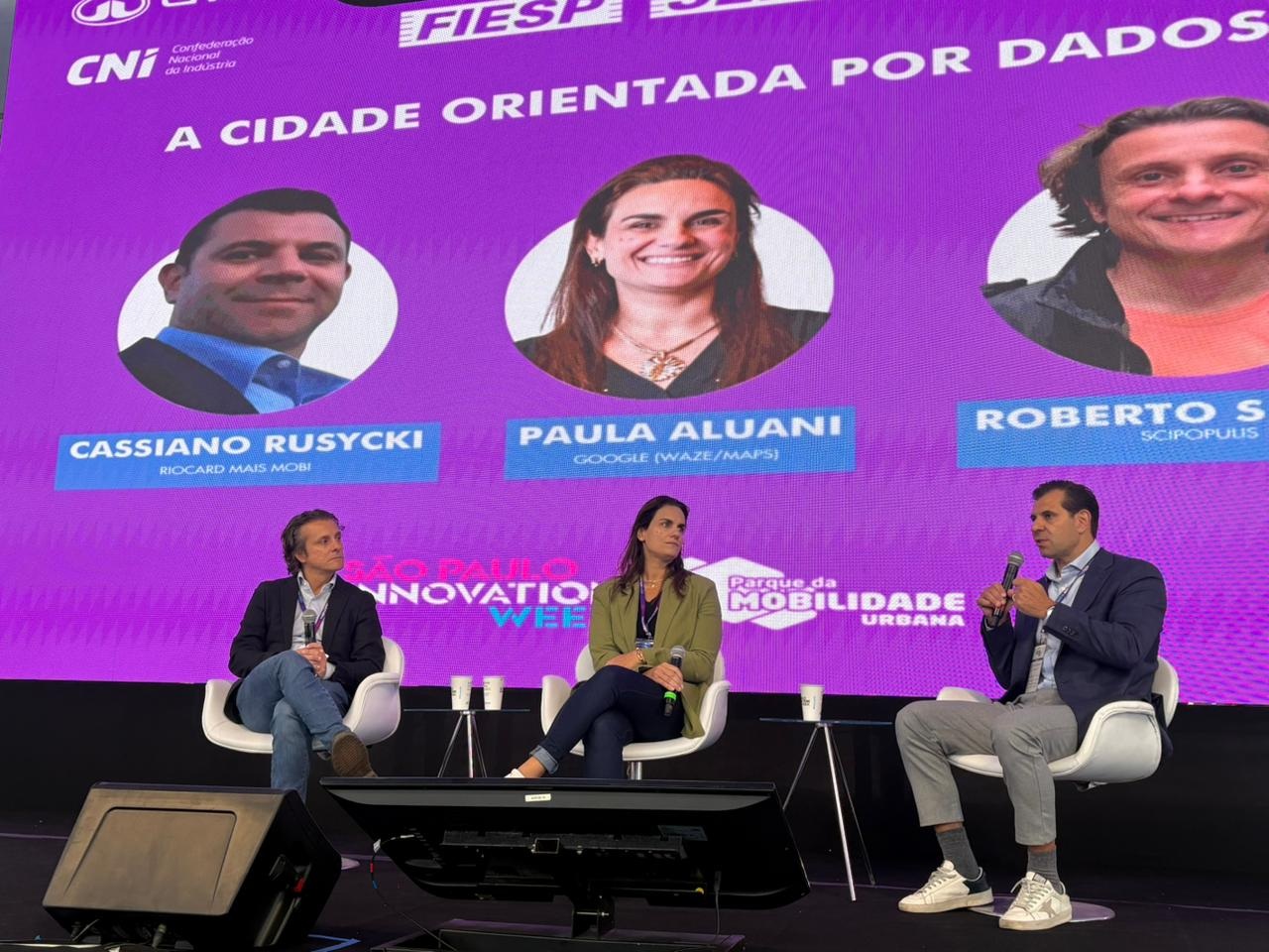 Cassiano Rusicky fala ao lado de Paula Aluani (Waze e Google Maps) e Roberto Speicys (Scipopulis)